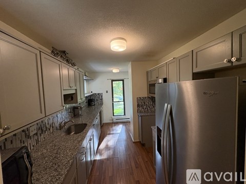 A kitchen with a stainless steel refrigerator and wooden floors.