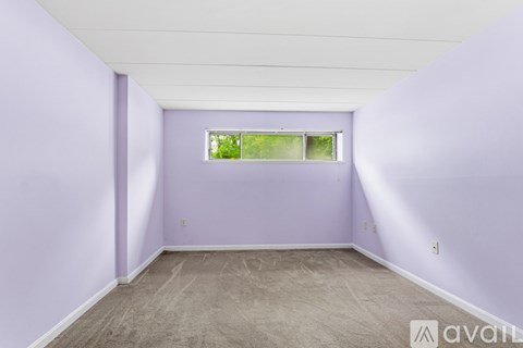 A room with purple walls and a window with a view of trees.
