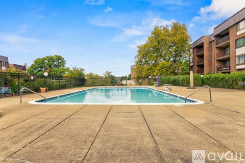 A swimming pool surrounded by a concrete floor and a black fence.