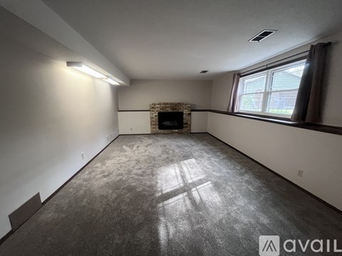A spacious room with a fireplace and a window.