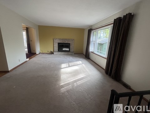 A spacious living room with a fireplace and large windows.