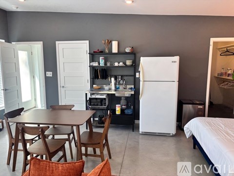 A kitchen with a table and chairs in the foreground and a fridge in the background.