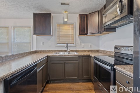A kitchen with dark wood cabinets and black appliances.