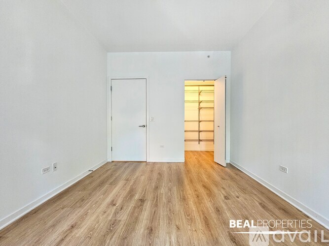 A room with wooden flooring and two doors, one of which is open.