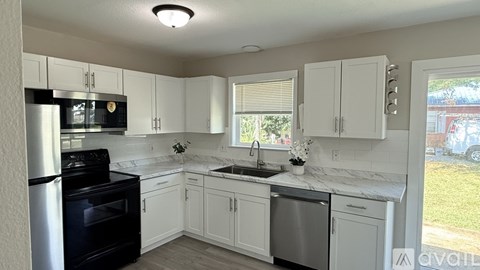 A kitchen with white cabinets and a black stove top oven.