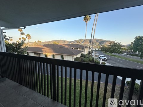 A balcony view of a residential area with houses and palm trees.