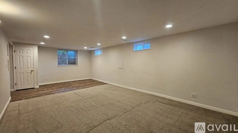 A spacious room with a carpeted floor and two windows.