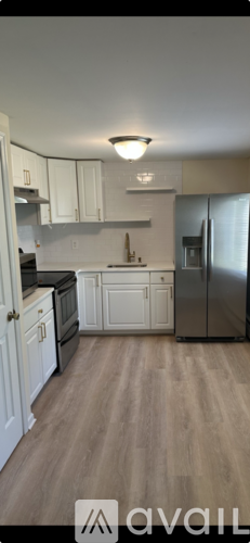 A kitchen with white cabinets and a refrigerator.