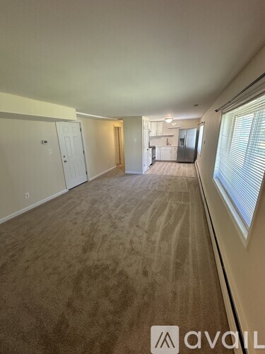 A long, empty hallway with carpeted floors and white walls.