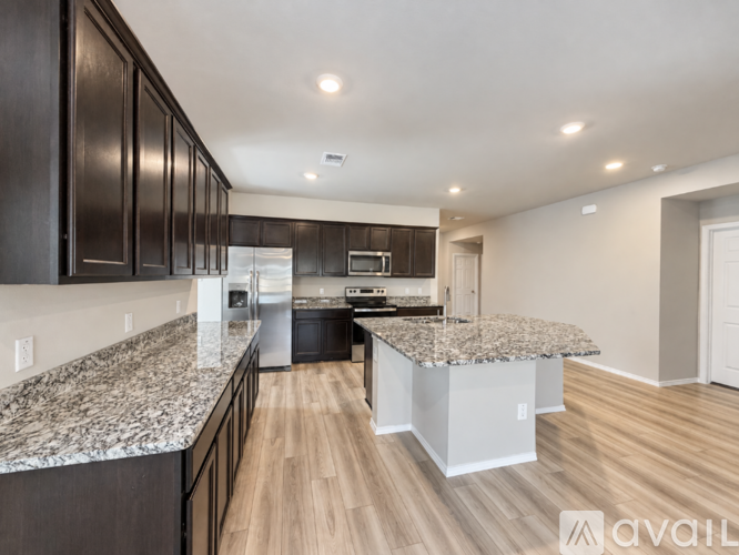 A modern kitchen with dark wood cabinets and a granite countertop.