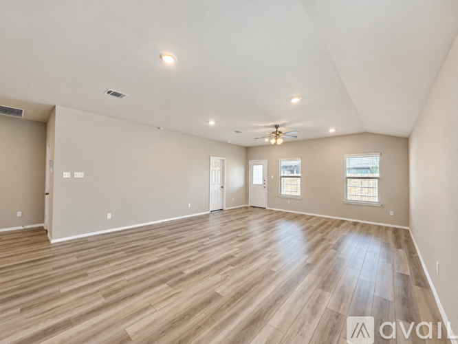 A spacious room with wooden flooring and a ceiling fan.