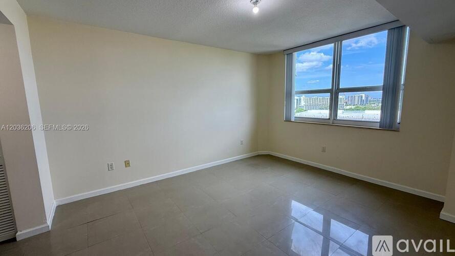 A spacious room with a large window overlooking a cityscape.