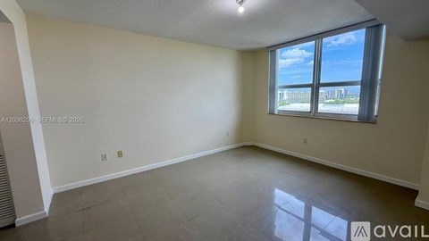A spacious room with a large window overlooking a cityscape.
