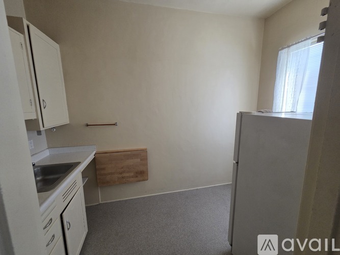 A kitchen area with white cabinets and a wooden cutting board.