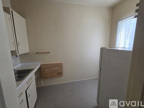 A kitchen area with white cabinets and a wooden cutting board.