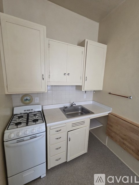 A small kitchen with a white stove and cabinets.