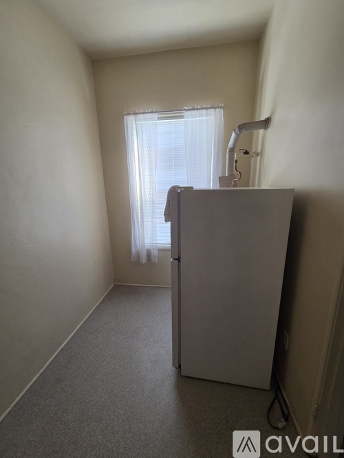 A room with a window and a grey refrigerator.
