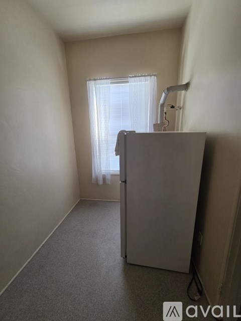 A room with a window and a grey refrigerator.