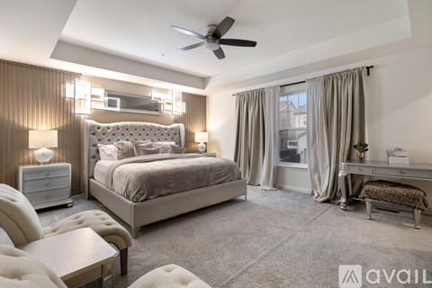 A bedroom with a large bed, a chair, and a ceiling fan.
