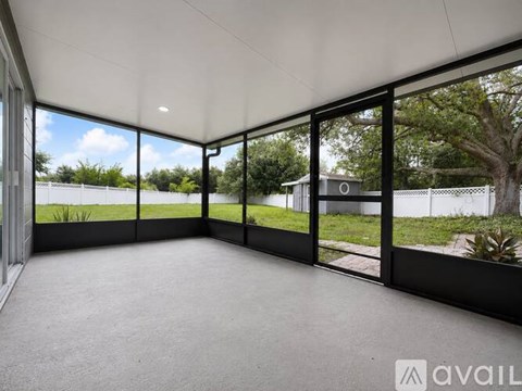 A spacious room with large windows overlooking a green landscape.