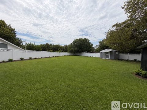 A backyard with a white fence and a small building.