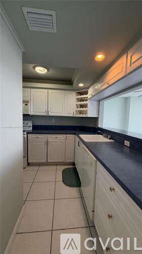 A kitchen with white cabinets and a black countertop.