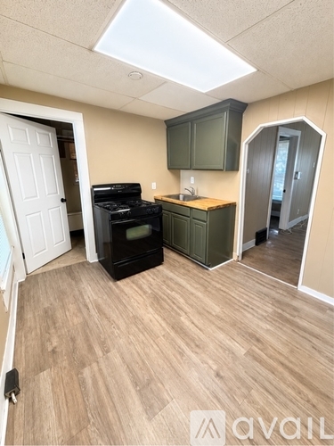 A kitchen with a black oven and wooden flooring.