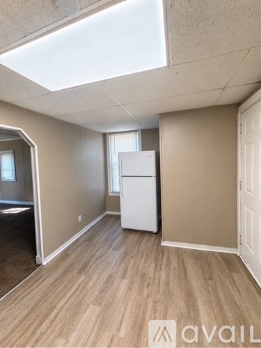 A kitchen area with a white refrigerator and wooden flooring.