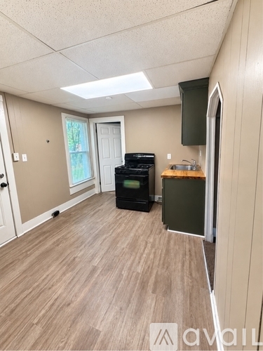 A kitchen with a black oven and a wooden floor.