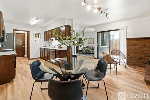 A modern living room with a glass table and black chairs.