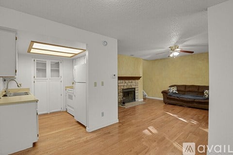 A living room with a couch, a fireplace, and a kitchen area with a refrigerator and sink.
