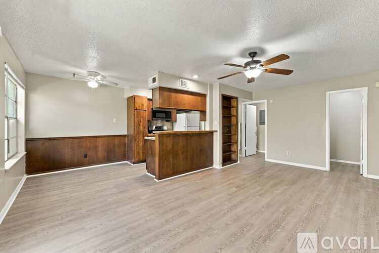 A spacious living room with a kitchenette and hardwood floors.