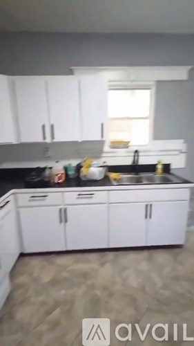 A kitchen with white cabinets and a black countertop.