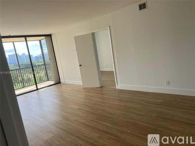 A room with wooden flooring and a large window overlooking a balcony.