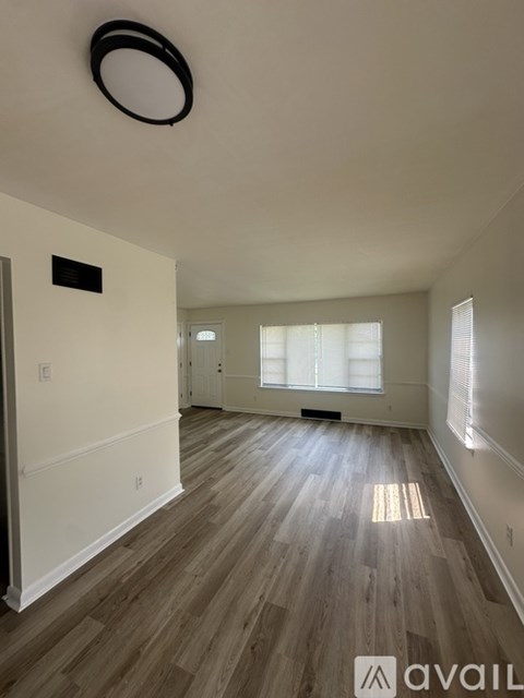 A spacious room with wooden flooring and a large window.
