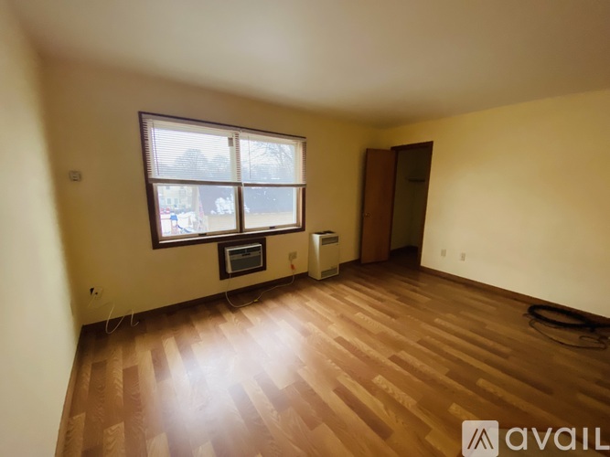 A room with wooden flooring and a window with blinds.