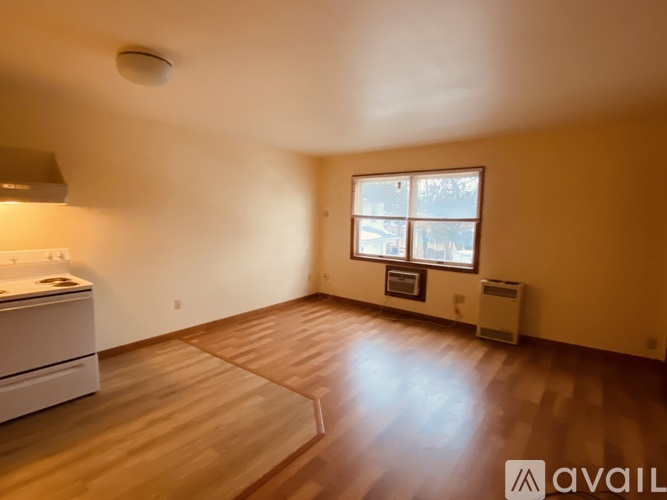 A room with wooden floors and a window with a view of buildings outside.