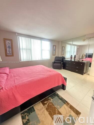 A bedroom with a pink bedspread and a rug on the floor.