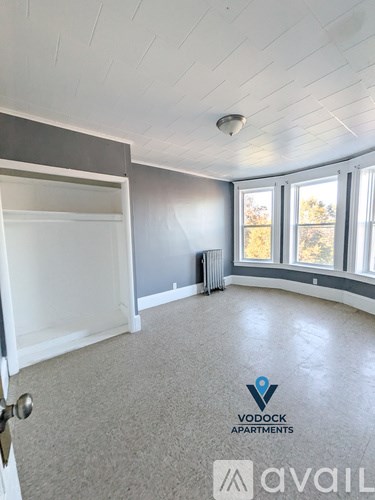 A room with a carpeted floor and a window with a view of trees outside.