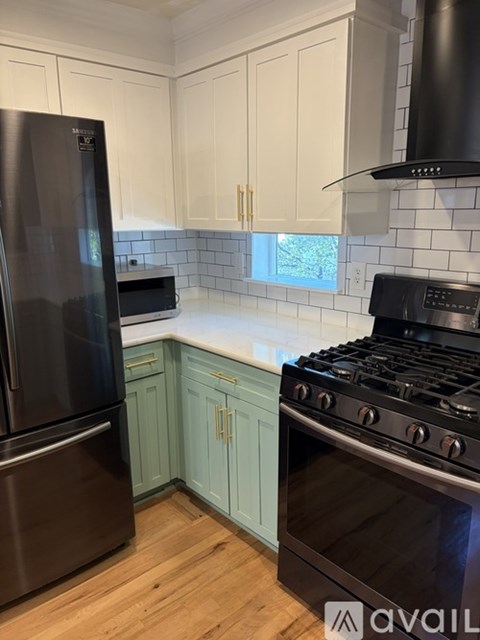A kitchen with a black refrigerator and a black stove top oven.