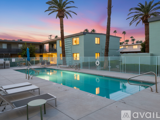 A pool surrounded by palm trees and apartment buildings.