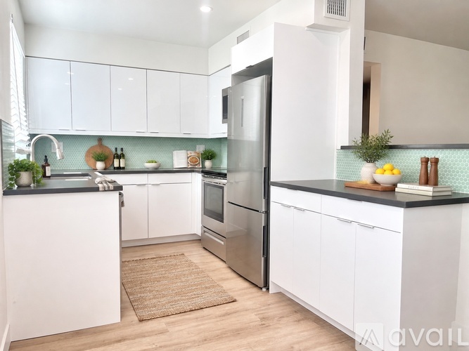 A kitchen with white cabinets and a black countertop.