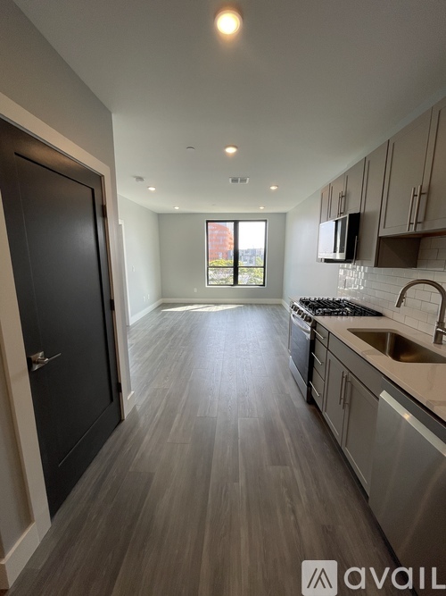 A kitchen with a black door and wooden flooring.