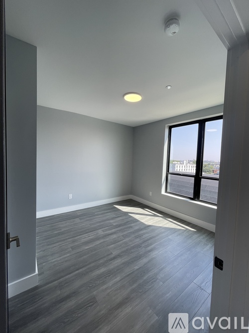A room with grey flooring and a window overlooking a cityscape.