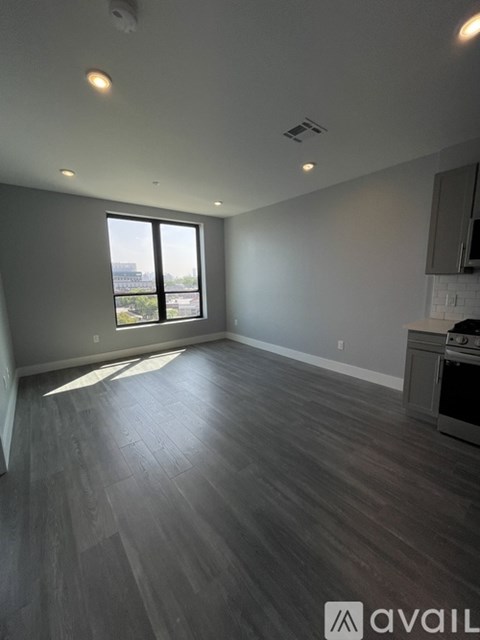 A spacious room with wooden flooring and a large window.