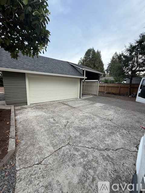 A driveway leads to a garage with a white van parked in front.