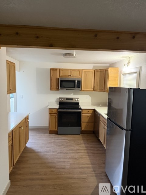 A kitchen with wooden cabinets and a black fridge.