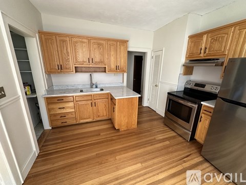 A kitchen with wooden cabinets and a stainless steel refrigerator.