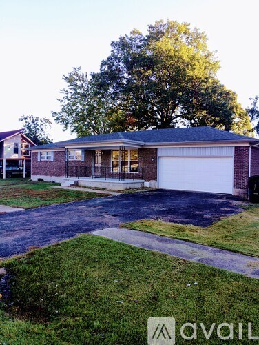 A house with a white garage door is in front of a tree.