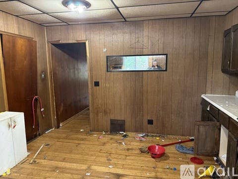 A room with wooden floors and walls, a television, and a refrigerator.